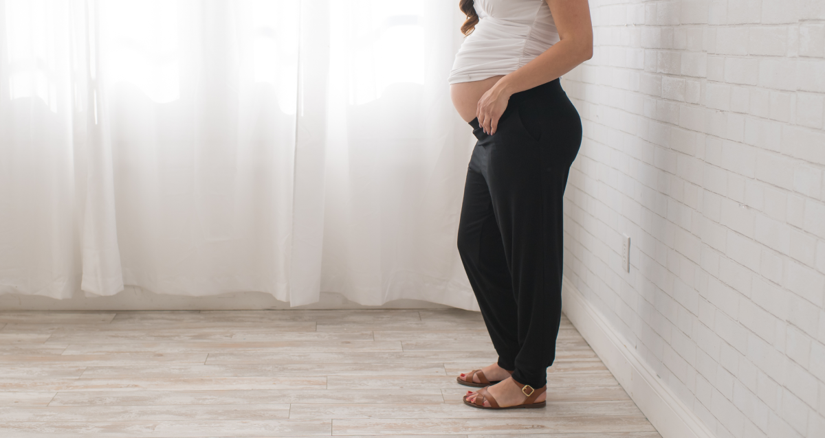 Expectant mother packing hospital bag with maternity clothes, pajamas, and robe for comfort and recovery