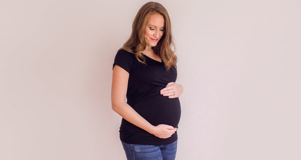 Pregnant woman in soft maternity leggings and a simple top at home, natural light