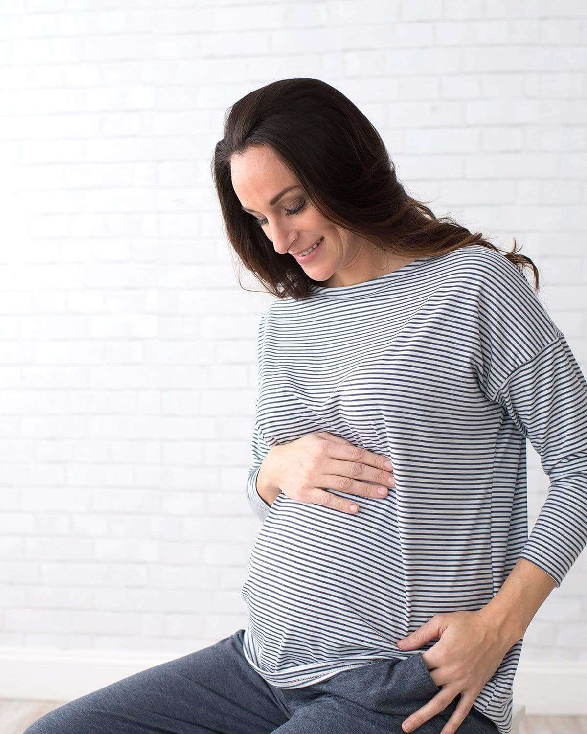 A pregnant woman wearing a long sleeve maternity dolman with a flattering boatneck.