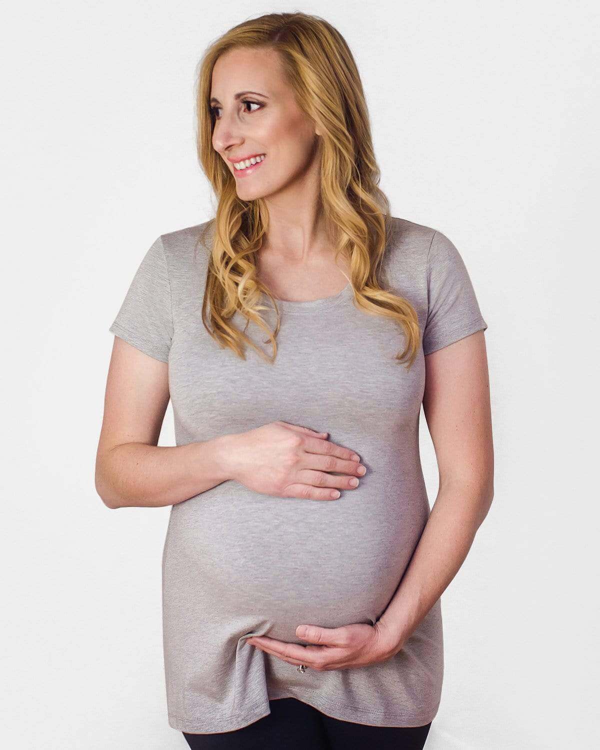 A pregnant woman wearing a black short sleeve maternity tee with a scoop neck.