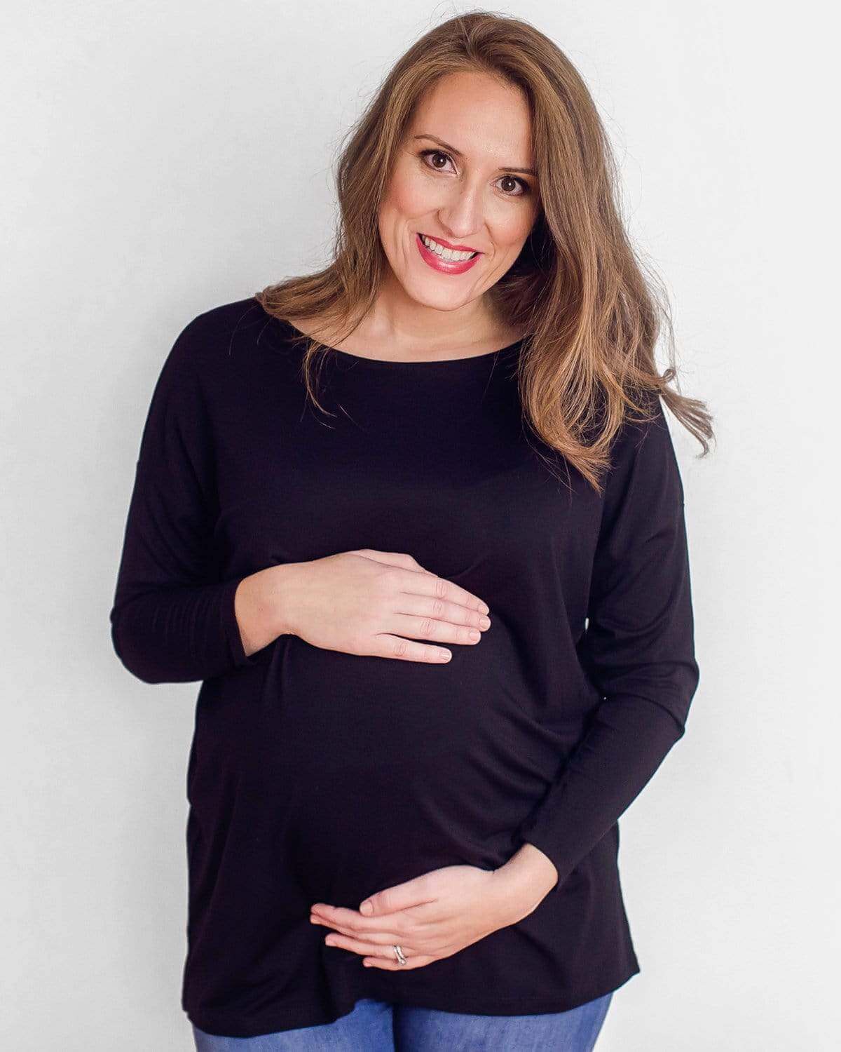 A pregnant woman wearing a long sleeve maternity dolman with a flattering boatneck.