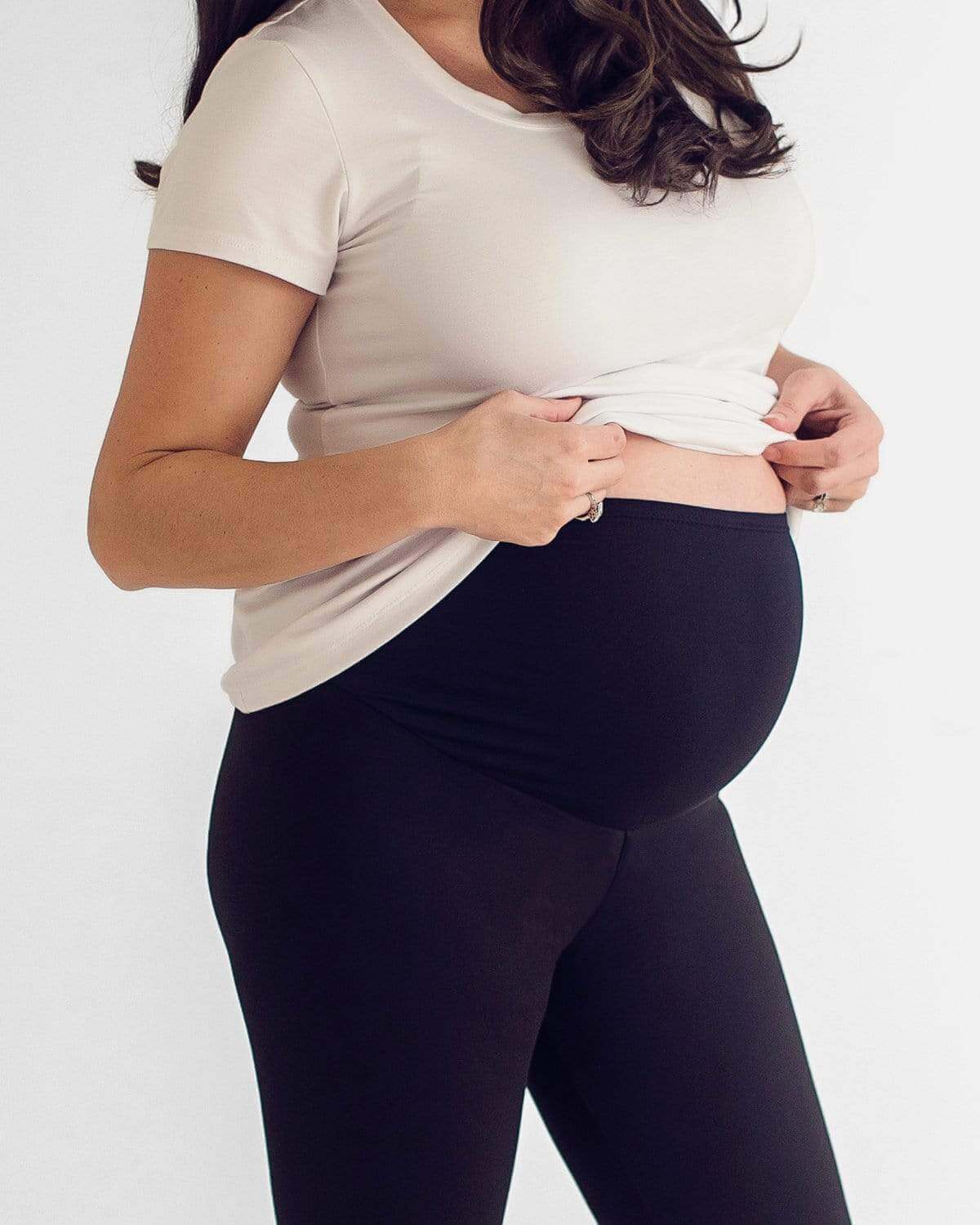 A pregnant woman wearing a white tank top and black maternity shorts with a comfortable belly panel.